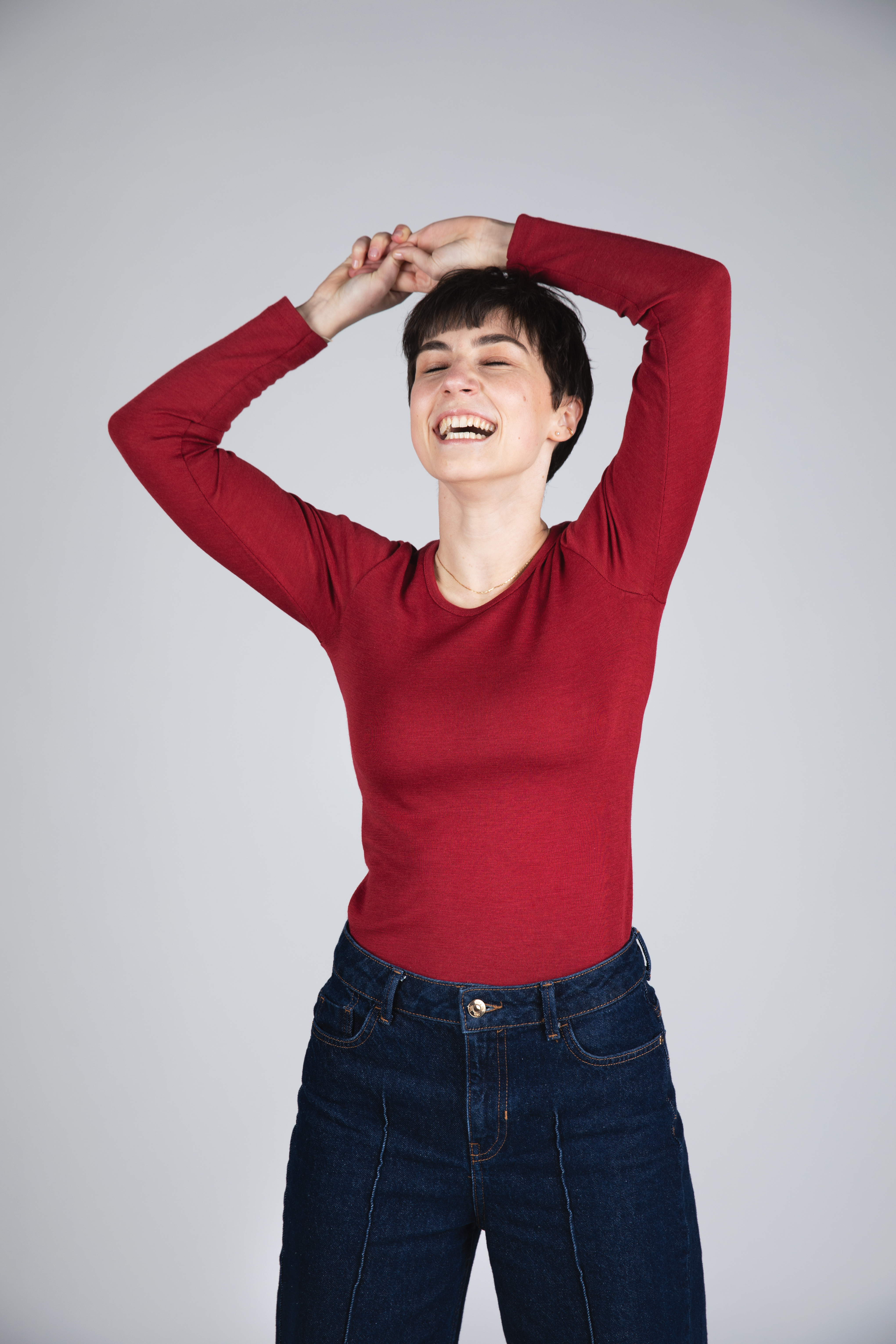 Frau trägt rotes langärmliges Merinowolle-Shirt von Engel und lacht entspannt.