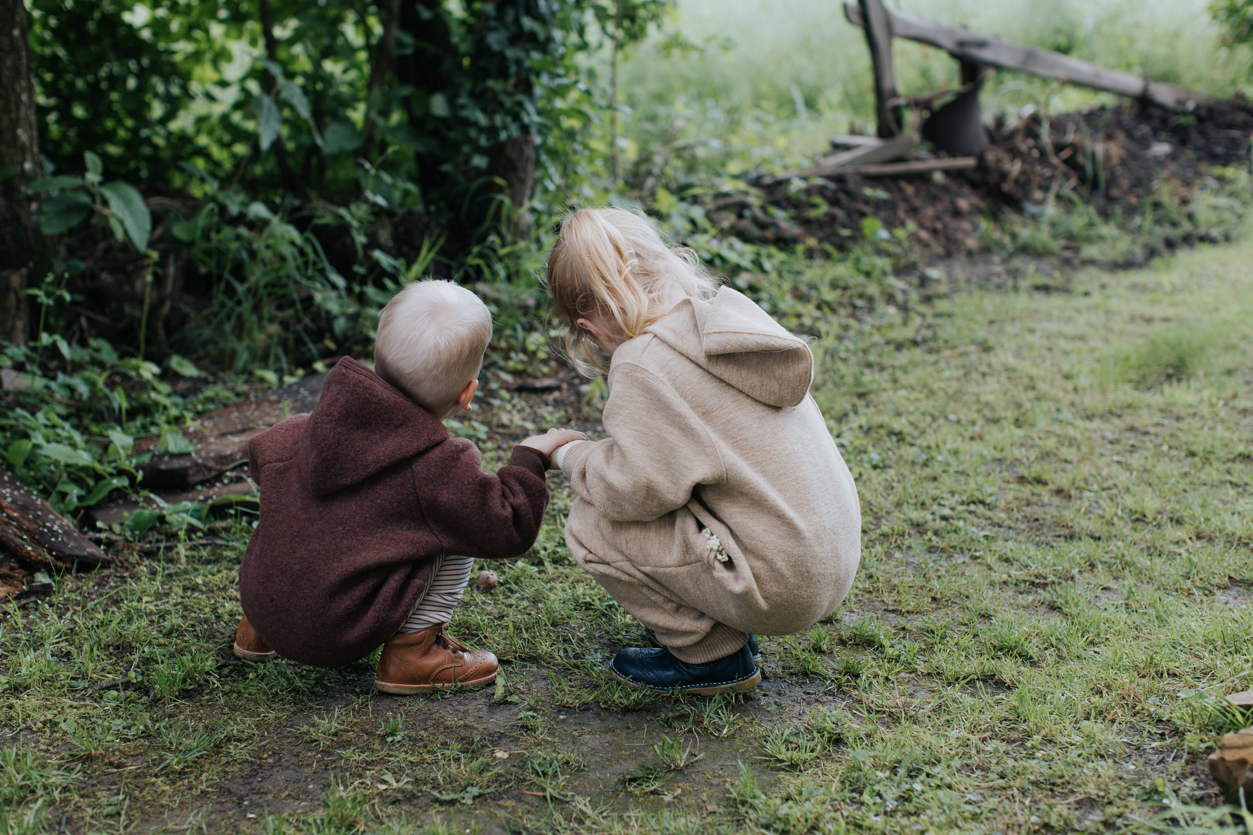 Kids dressed in wool fleece and wool walk from Engel are digging around in nature, searching for little treasures on the ground.