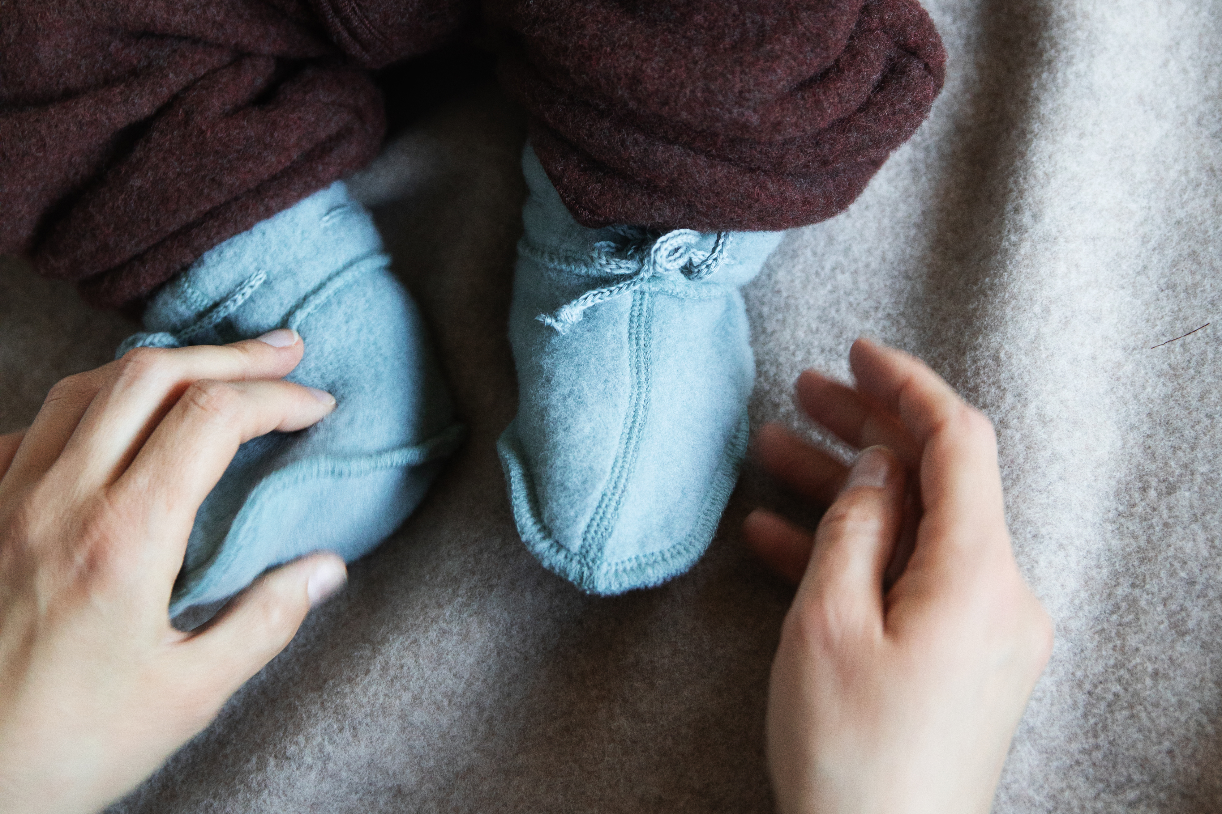 Baby feet wrapped snugly in soft merino wool fleece.